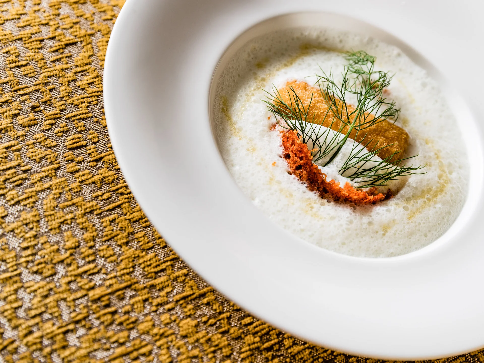 Ihr Hotel in Tramin: ein Genussort inmitten der Weinberge Feine Suppe mit Schaum, Crostini und Dill in weißem Teller