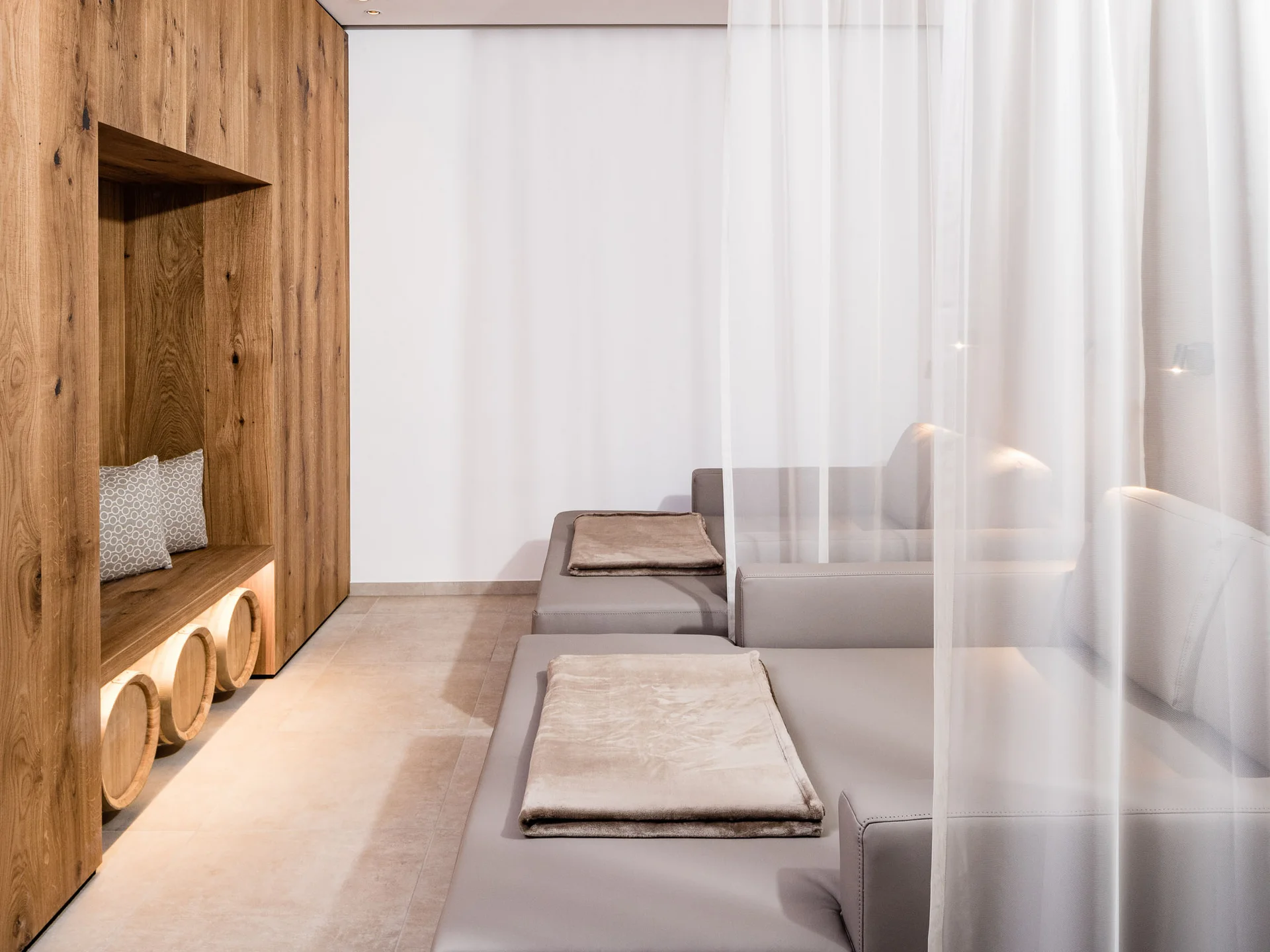 Ihr Hotel in Tramin: ein Genussort inmitten der Weinberge Moderner Ruheraum mit grauen Liegen und Holzwand mit Sitznische